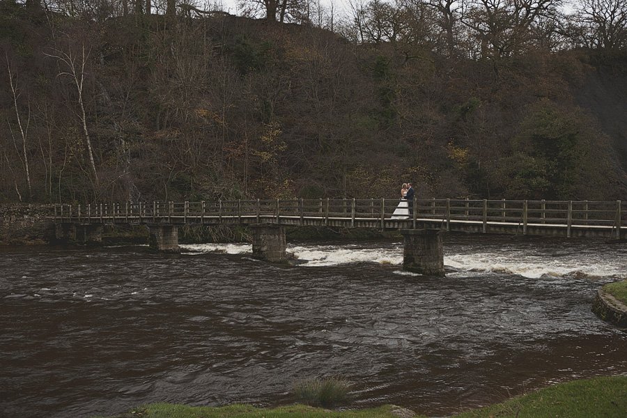 Bride and groom on wooden bridge over river
