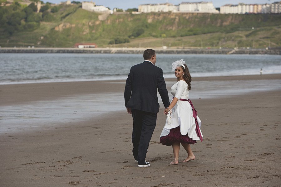 Couple in wedding attire walking on beach