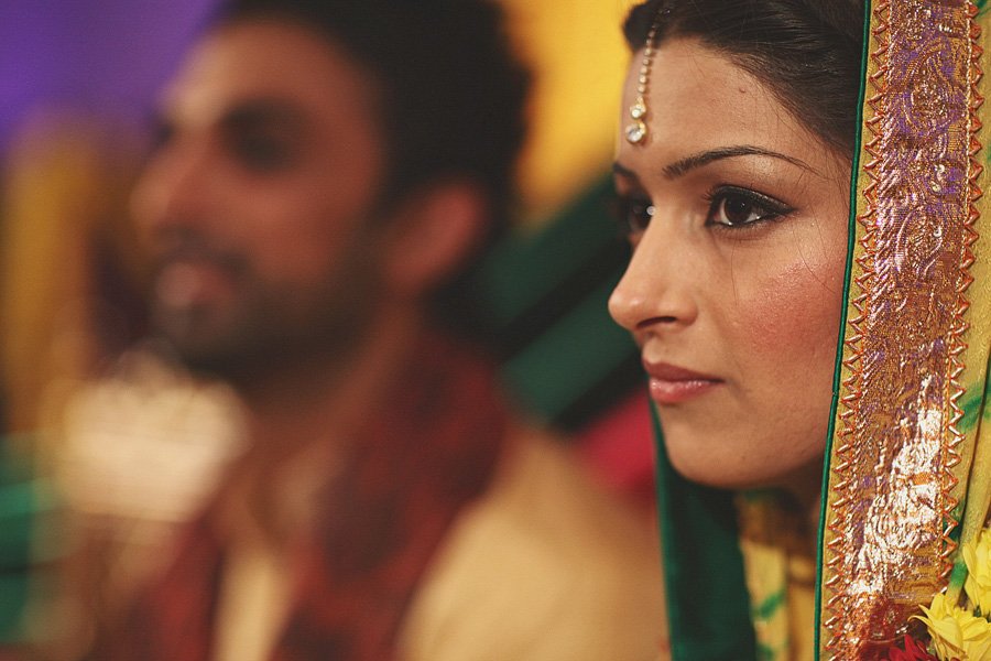 Bride in traditional attire with groom blurred behind