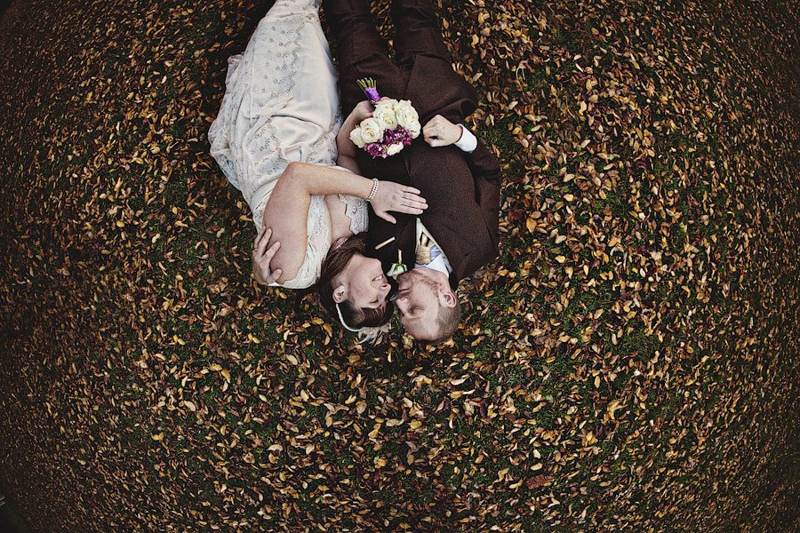 Bride and groom lying on autumn leaves