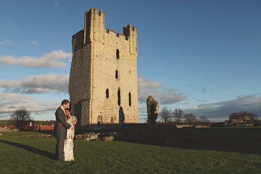 Couple embracing beside historic stone tower at sunset