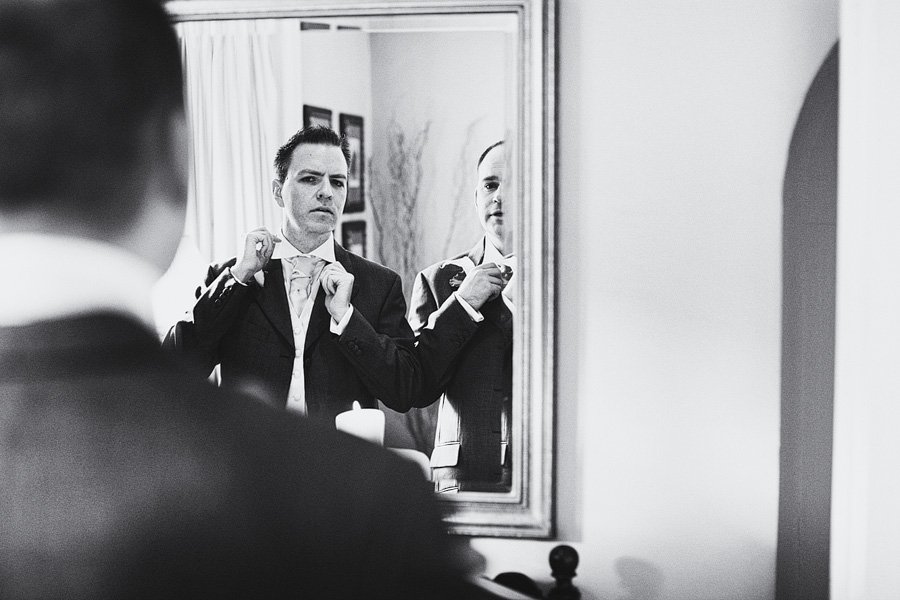 Man adjusting tie in mirror