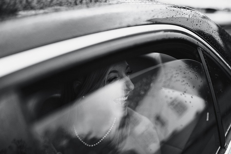Smiling woman inside car on rainy day