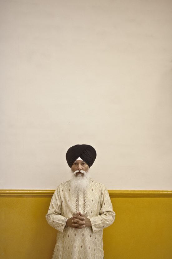 Elderly man in turban against two-tone wall