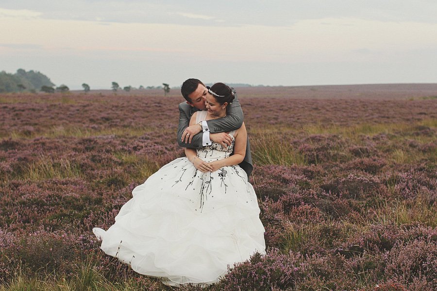 Bride and groom embracing in purple heather field