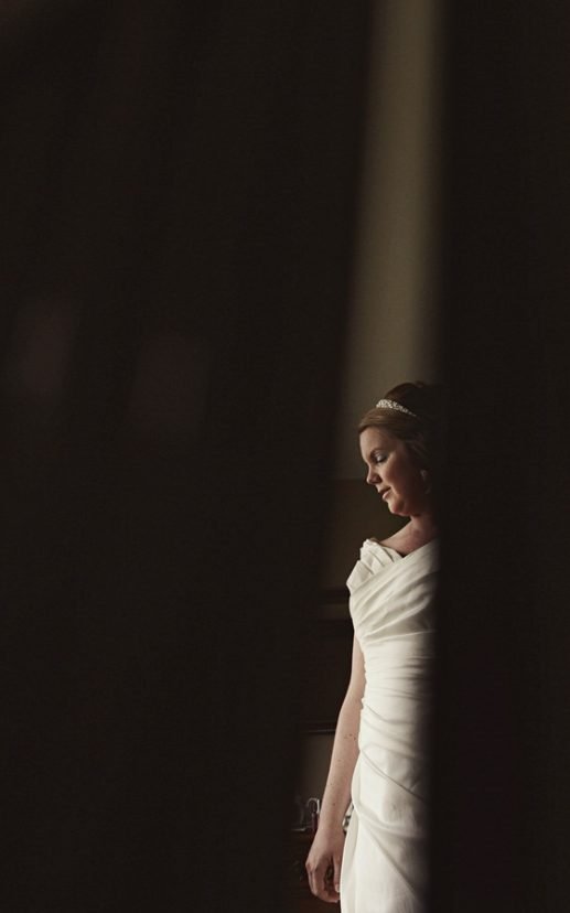 Bride in white wedding dress by window