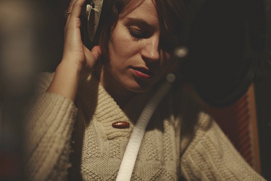 Woman singing into microphone in recording studio