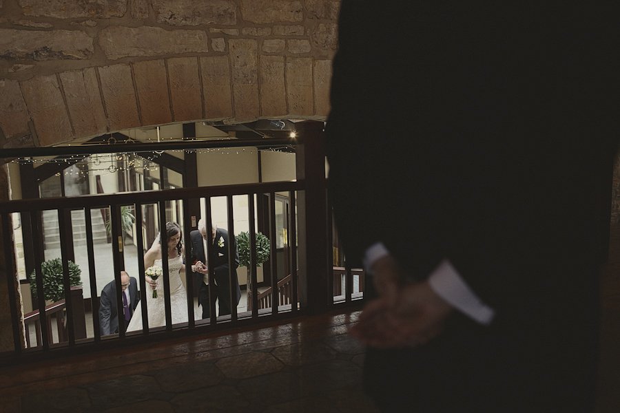 Bride ascending staircase with attendants watching