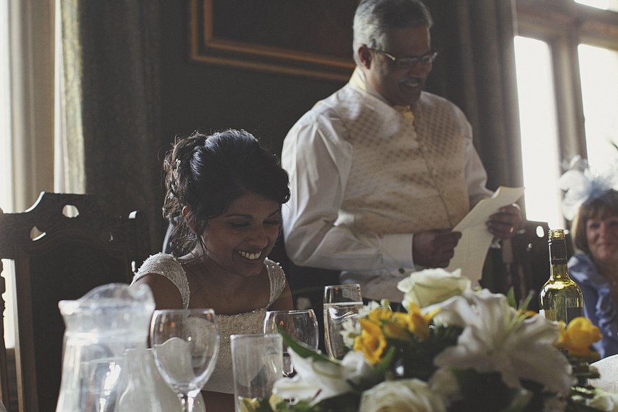 Bride smiling during wedding speech at reception table