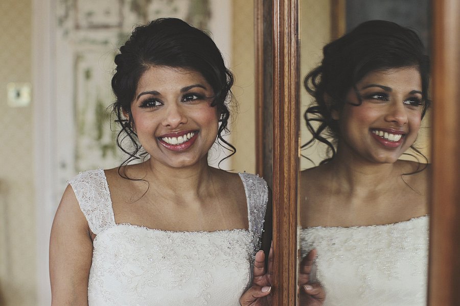 Smiling bride beside mirror with reflection