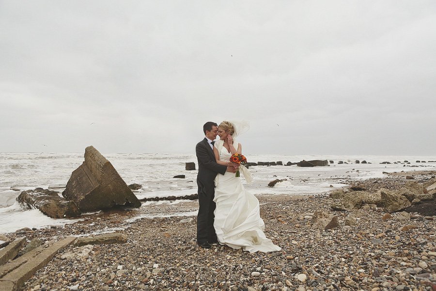 Bride and groom embracing on rocky beach