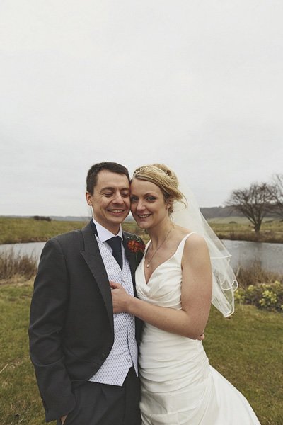 Bride and groom posing outdoors by lake