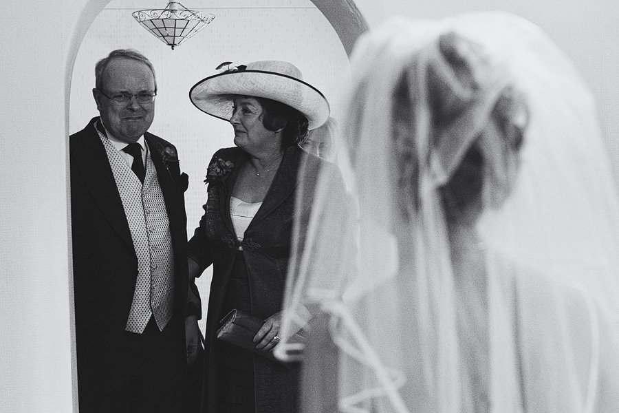 Bride facing older couple under archway