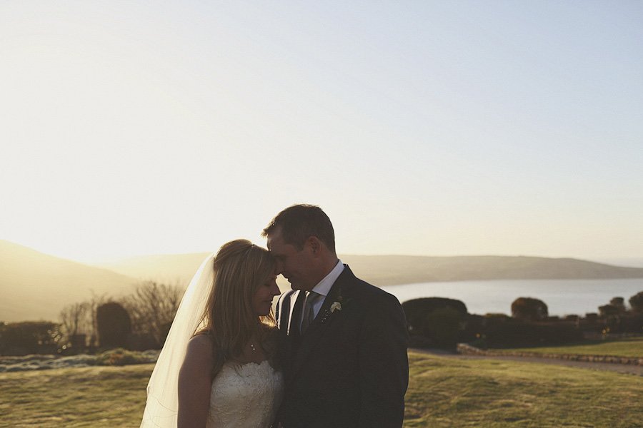 Bride and groom embracing at sunset outdoors