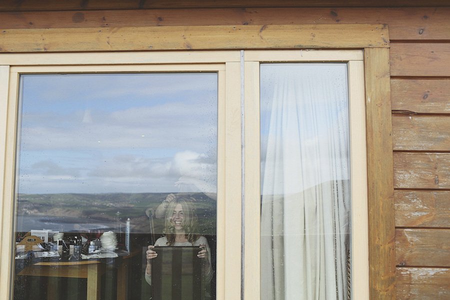 Woman holding tablet behind window with landscape reflection
