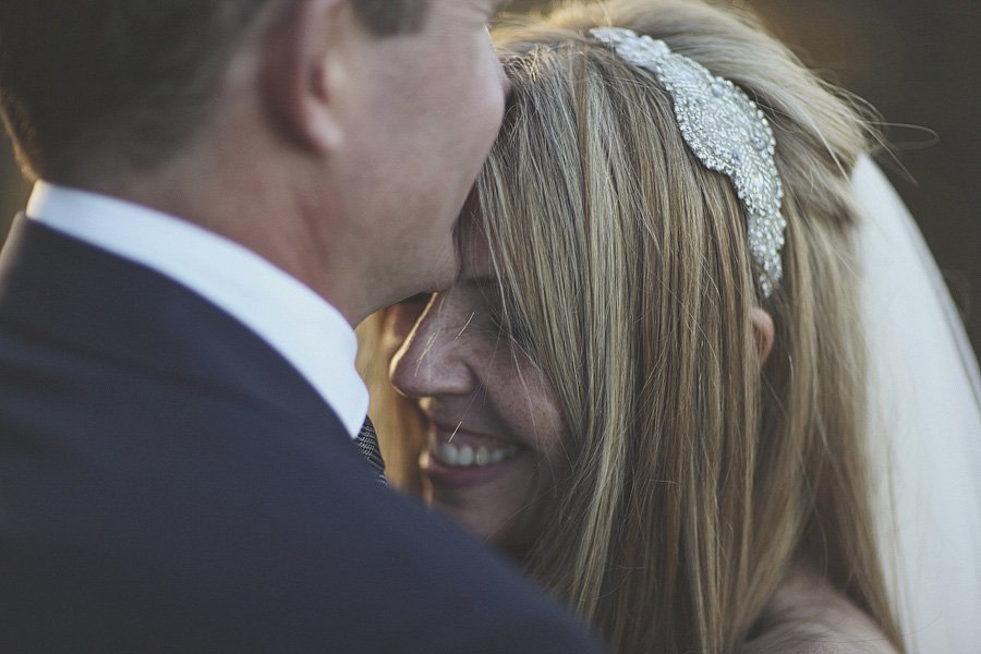Bride smiling while embracing groom on wedding day