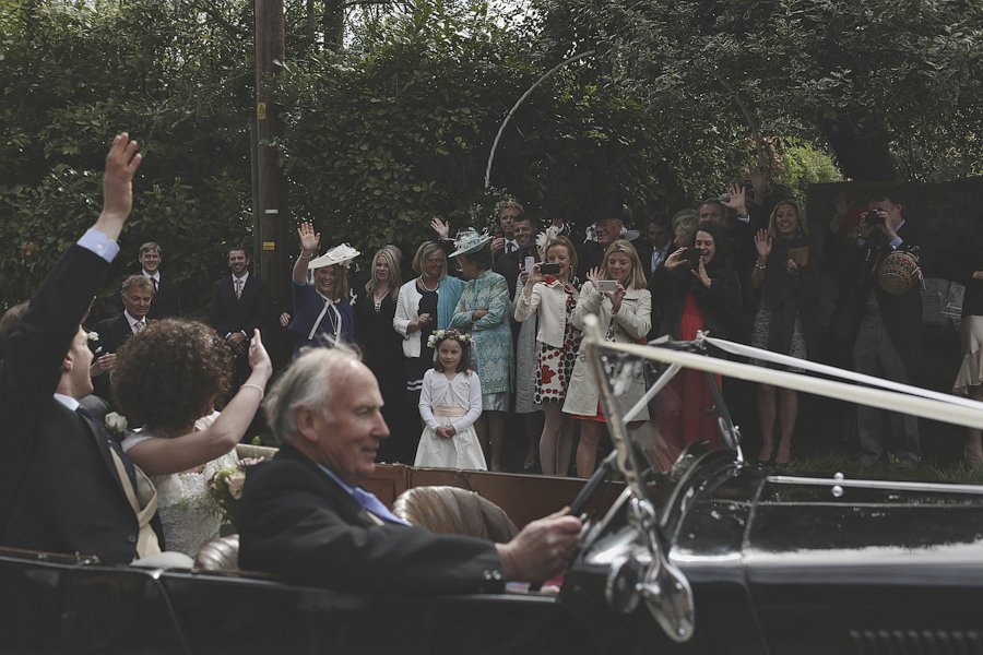 Wedding couple leaving in vintage car waving