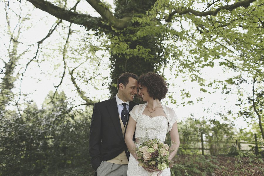 Bride and groom smiling under leafy tree