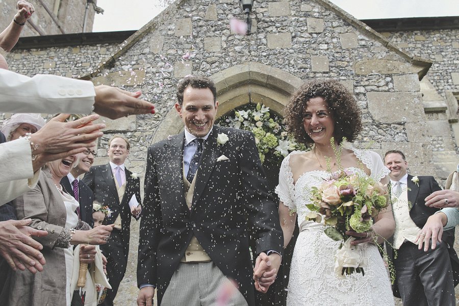 Bride and groom exiting church under confetti