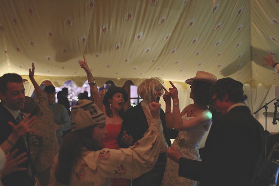 Wedding guests dancing under decorated reception tent