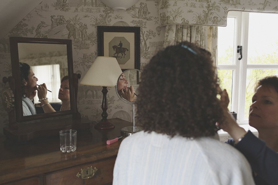Woman applying makeup at bedroom vanity mirror
