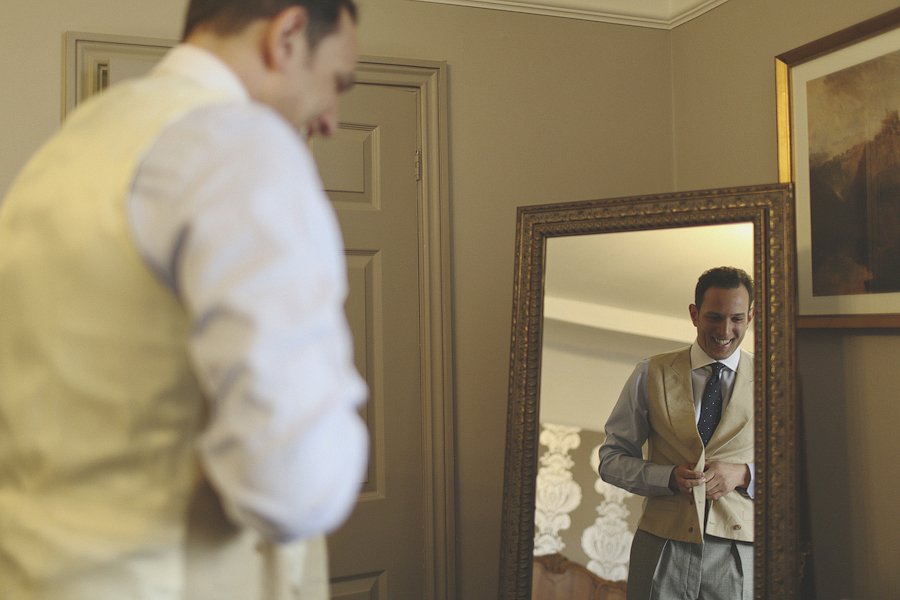 Man adjusting vest in front of mirror