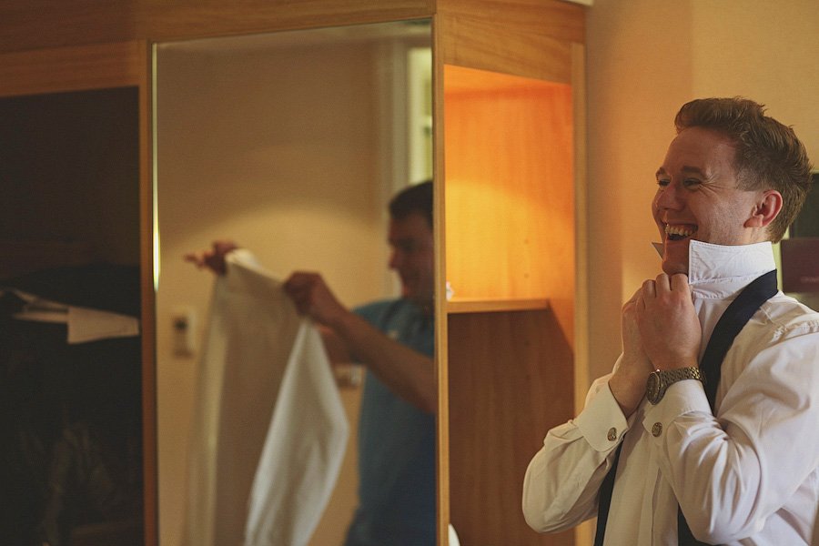 Man adjusting bow tie in mirror