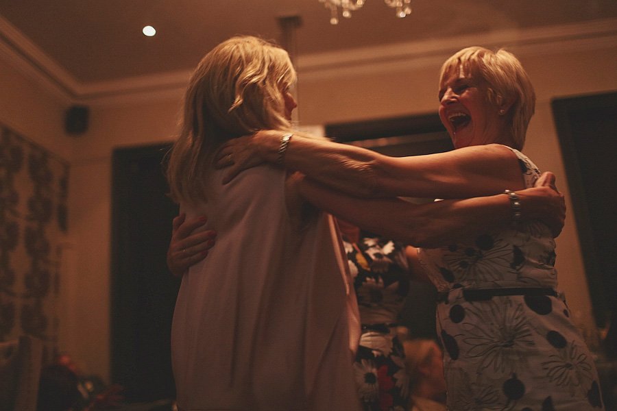 Two women hugging and laughing indoors at party
