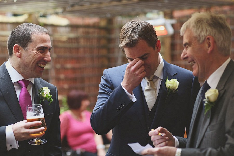 Three men in suits laughing at wedding