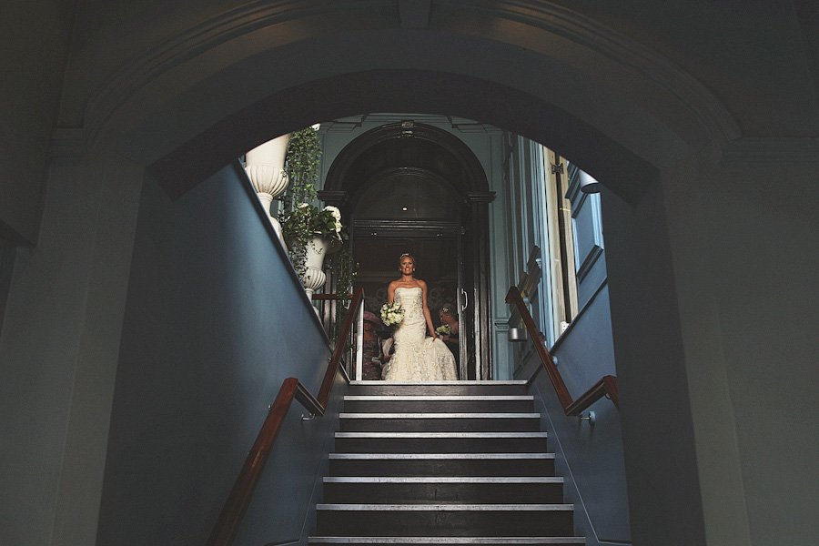 Bride in wedding gown at top of staircase