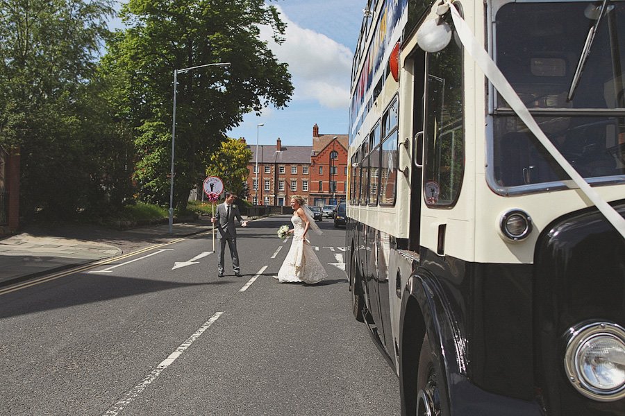 Bride and groom crossing street beside vintage bus