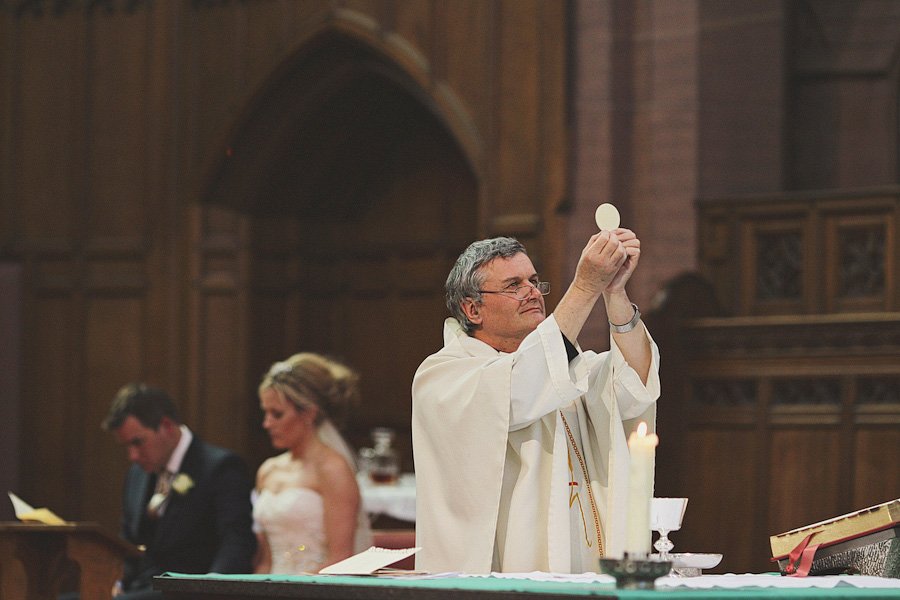 Priest elevating communion host during church wedding ceremony