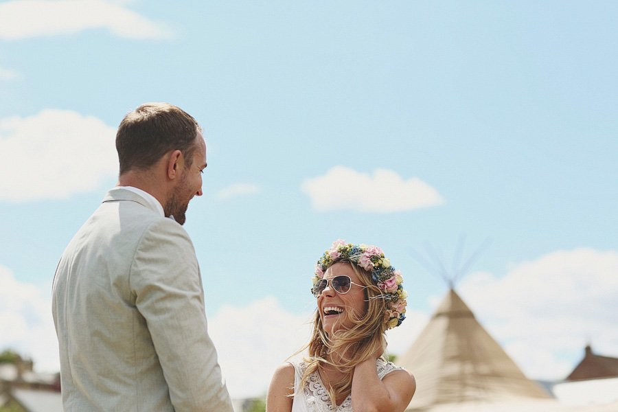 Smiling couple outdoors with flower crown and teepee