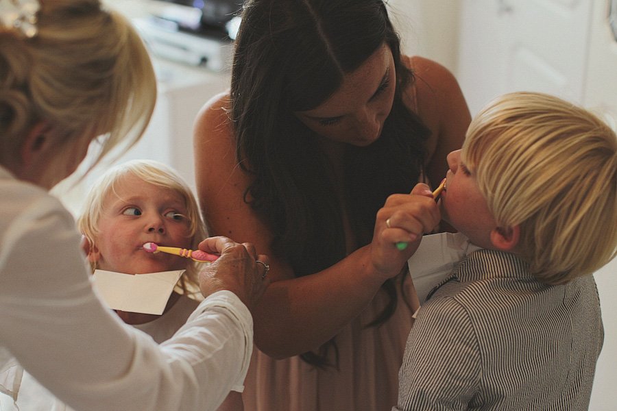 Mothers helping children brush teeth in bathroom