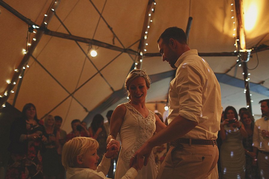 Bride and groom dancing with child under lights