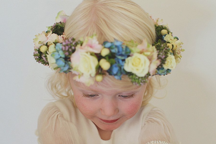Blonde child wearing colorful flower crown looking down