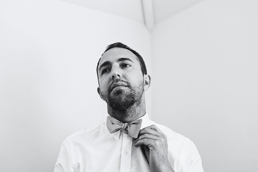 Man adjusting bow tie in black and white
