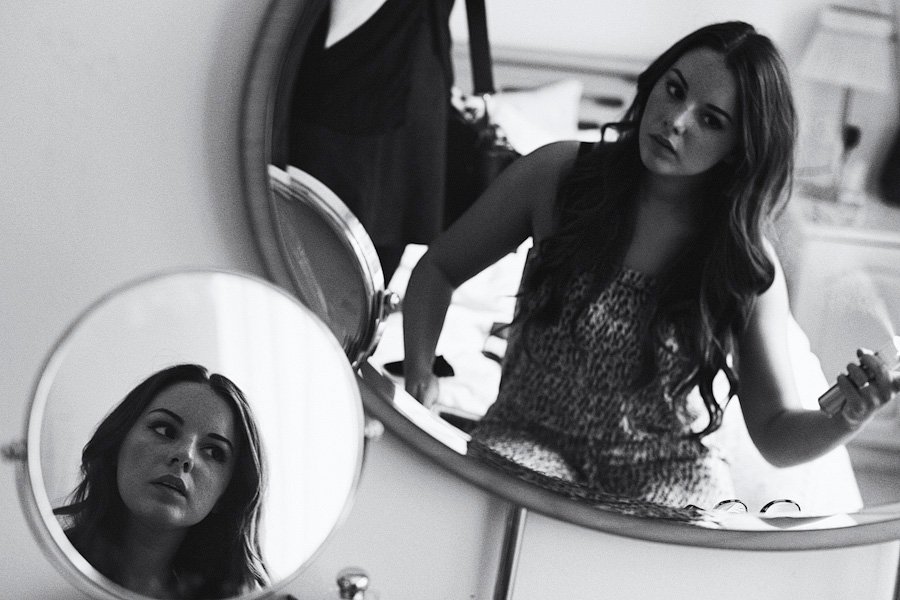 Woman looking into vanity mirror in black and white