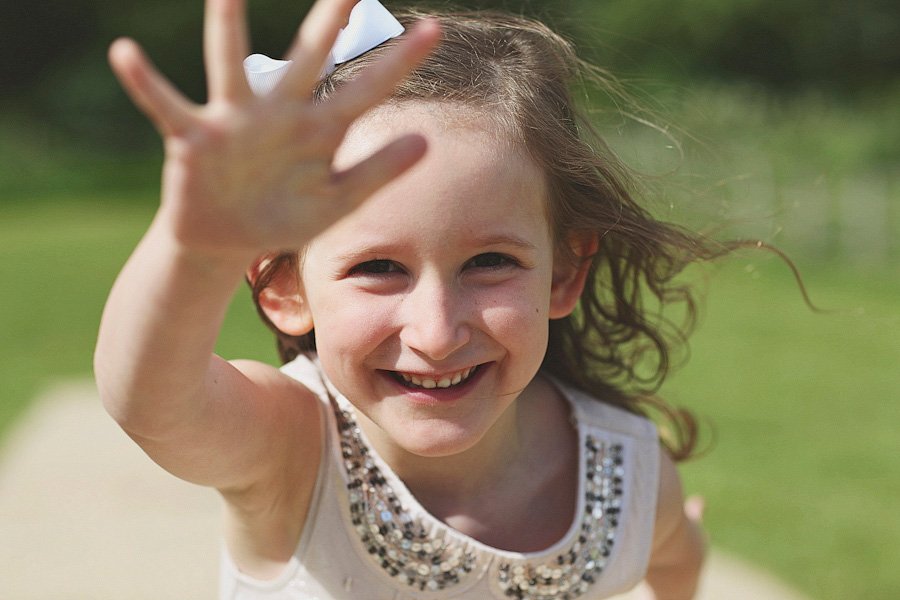 Smiling young girl reaching toward camera outdoors