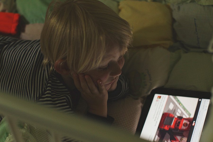 Child lying on bed watching tablet at night