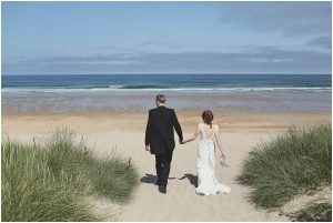 Bride and groom walking toward ocean beach
