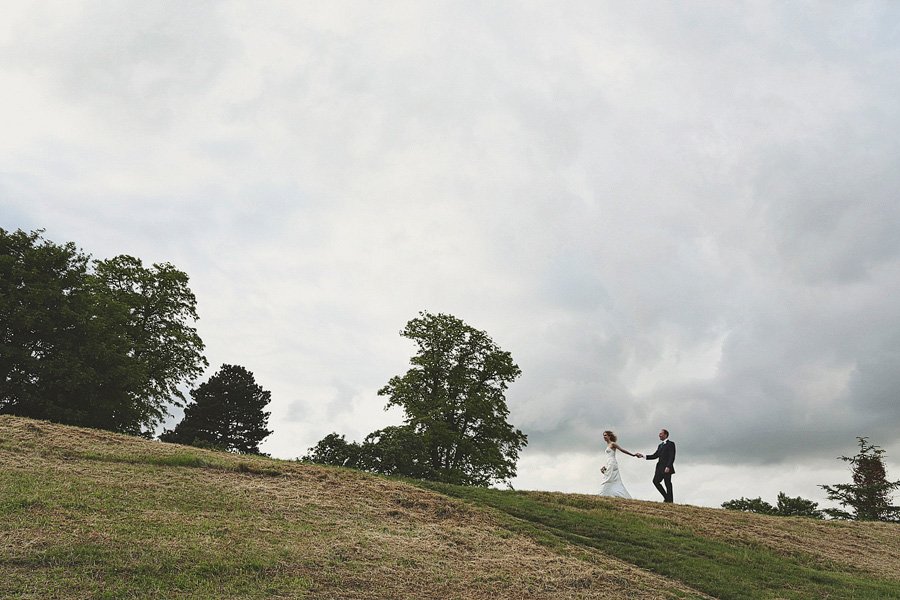 Bride and groom walking on grassy hill