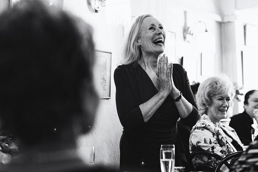 Older woman smiling and clapping at dinner table