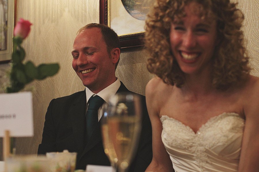 Bride and groom laughing at wedding reception table
