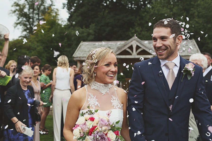 Bride and groom walking under falling confetti