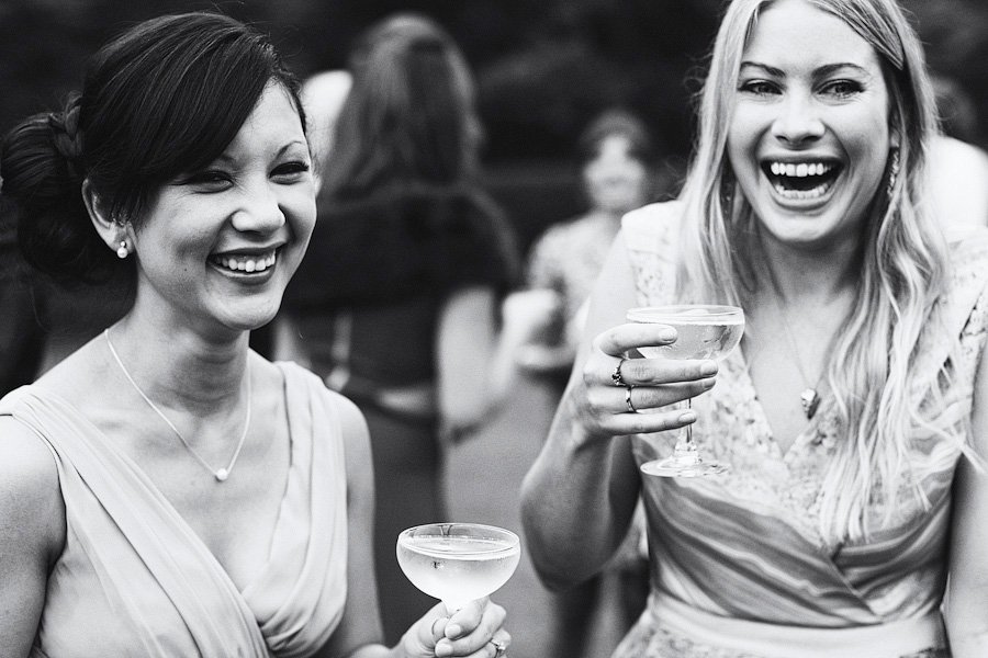 Two women laughing with cocktails at outdoor event