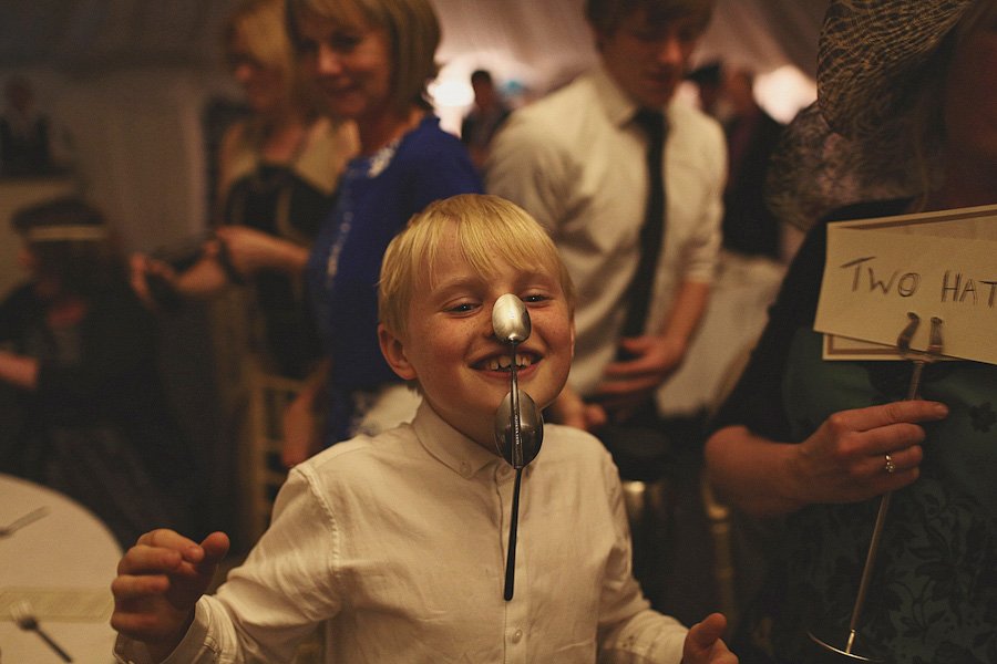 Boy balancing spoons on face at party