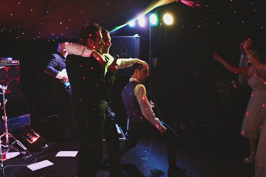 Men in suits dancing under colorful party lights