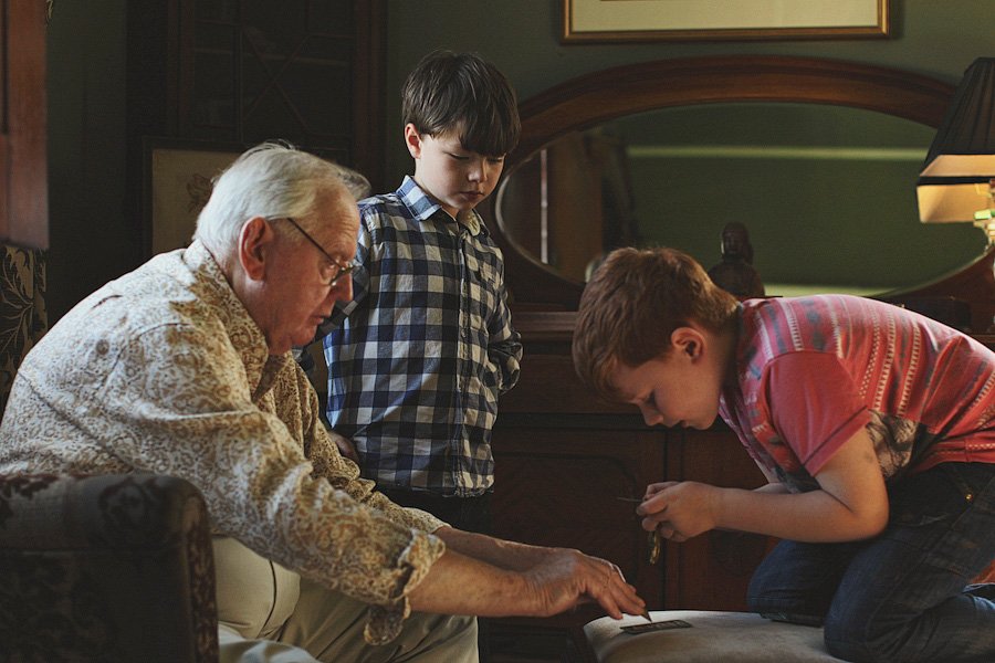 Grandfather and two boys examining object together