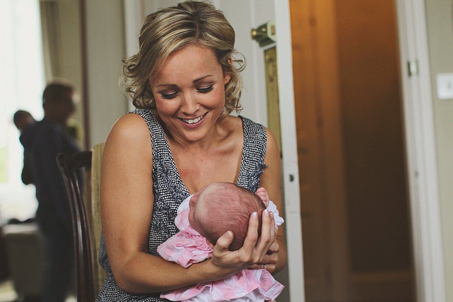 Mother smiling while holding newborn baby indoors